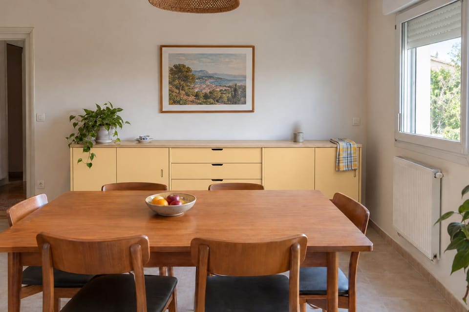 Salle à manger, long buffet bas aux portes et tiroirs jaune moutarde, dessus en chêne pâle, table et chaises au premier plan. Portes et tiroirs Honey Mustard RM16, dessus Pale Oak AG13. Image d'ambiance aux teintes du catalogue.