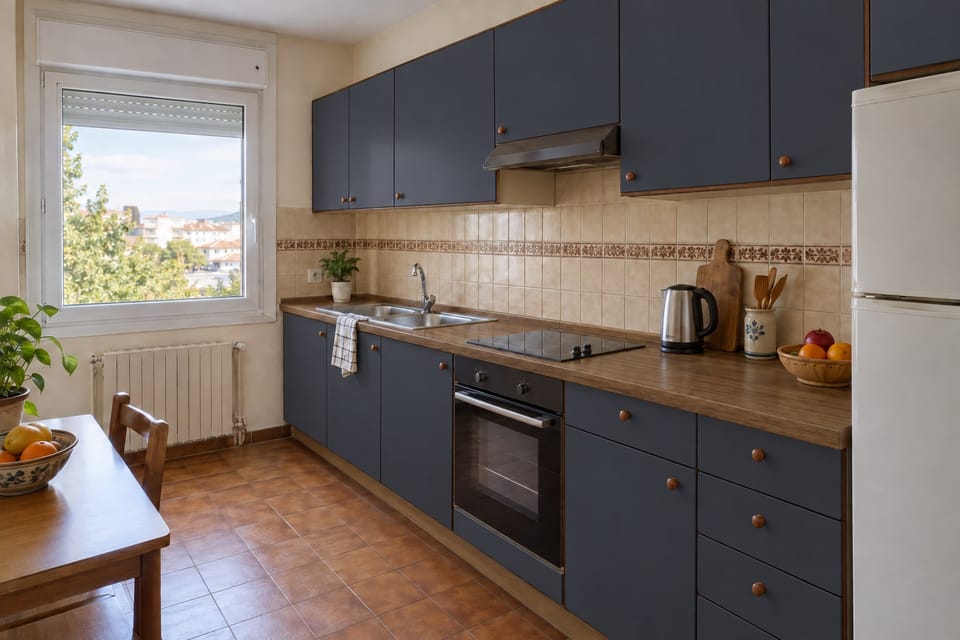 Cuisine des années 1980 sur un mur, façades bleu nuit mates, plan de travail en chêne, carrelage à frise gardé. Façades Midnight Blue M9, plan de travail Original Oak AA14. Image d'ambiance aux teintes du catalogue.
